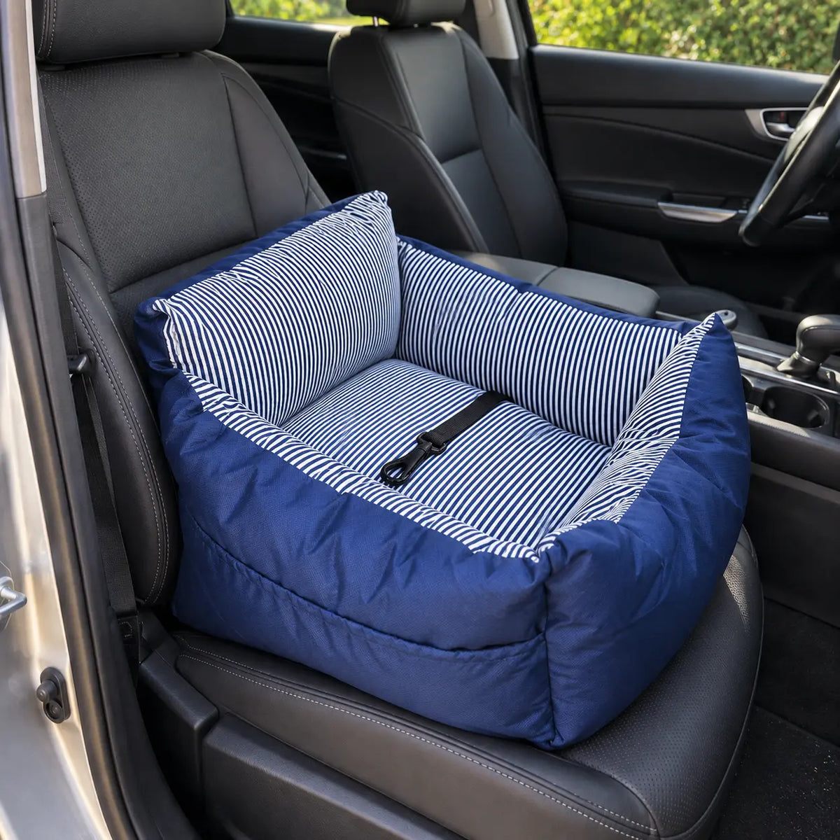 A blue and white striped pet car seat cushion with a black harness strap, shown installed on a car seat.