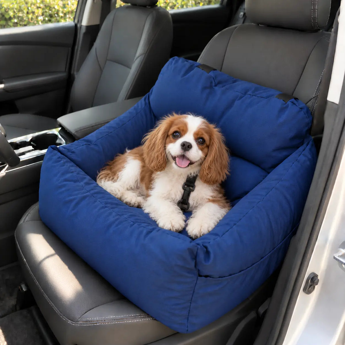 A small brown and white dog sits comfortably inside a blue car seat pet booster seat installed on a gray leather car seat.