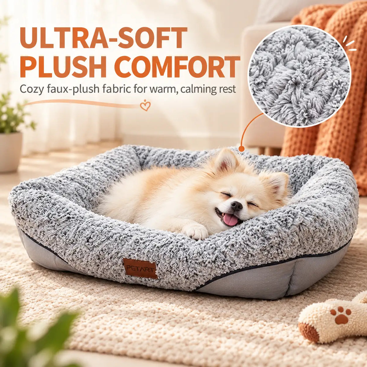 A small cream-colored dog rests inside a plush, square pet bed with a gray faux-plush fabric. The scene is set in a cozy, warm-toned room with a textured rug, a knit blanket, and a small toy, with promotional text highlighting the ultra-soft comfort of the bed.
